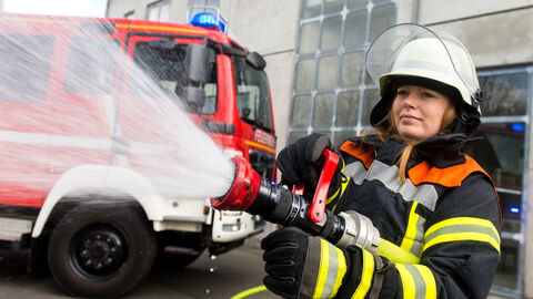 Feuerwehrfrau im Einsatz, Löschsituation mit Wasserschlau.
