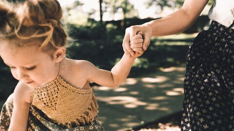 Mutter hält ihre Tochter an der Hand.