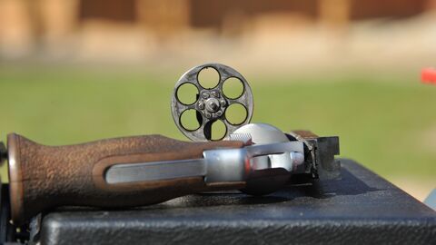 Revolver mit ausgeklappten Magazin auf einem Schießstand liegend.