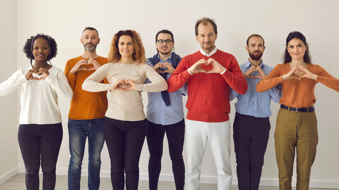 Frauen und Männer, die ihre Hände zu einem Herz formen