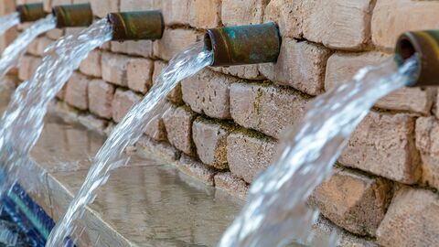 Grundwasserschutz und -versorgung Wasserrohre aus einer Steinwand mit Trinkwasser