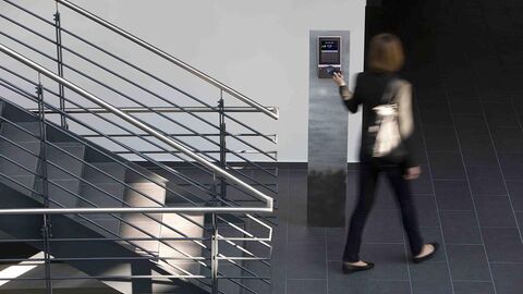 Person geht an einem Zeiterfassungsgerät vorbei und stempelt sich zum Dienstantritt ein.