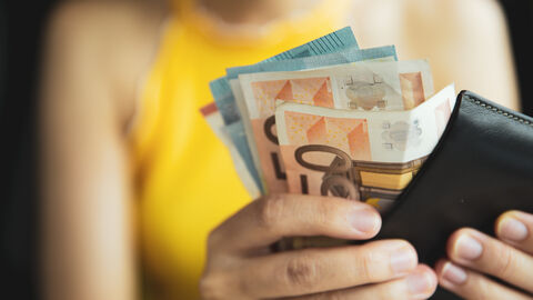 Frau mit Geldbörse und Euro-Scheinen in der Hand.