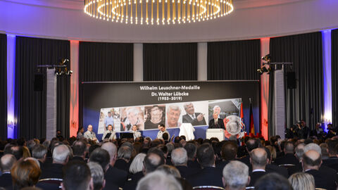 Wilhelm Leuschner-Medaille an Dr. Walter Lübcke Leinwand mit Bildern von Dr. Walter Lübcke vor den Gästen der Verleihung.