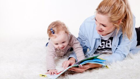 Tagespflege Frau schaut mit einem Kind ein Buch an