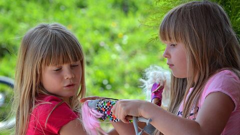 Zwei Mädchen spielen mit einer Puppe