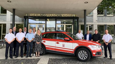 Teilnehmende neben einem Feuerwehrauto vor dem Haupteingang des Regierungspräsidiums Kassel.