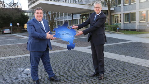 Regierungspräsident Mark Weinmeister bekommt von Regierungspräsident a. D. Hermann-Josef Klüber den Regierungsbezirk Kassel, in Form einer Schablone, übergeben.