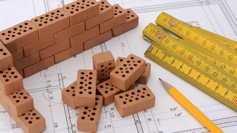 Zollstock, Bleistift und Ziegelsteine auf einem Bauplan