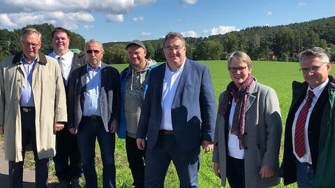 Regierungspräsident Mark Weinmeister und weitere Besuchende in Bad Hersfeld vor einer grünen Wiese.