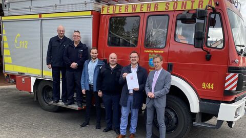 Regierungsvizepräsident Dr. Wachter übergibt Bescheid vor einem Feuerwehrauto.
