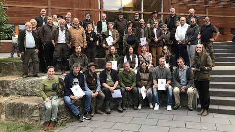 Die neuen Falknerinnen und Falkner mit der Prüfungskommission auf einer Treppe.