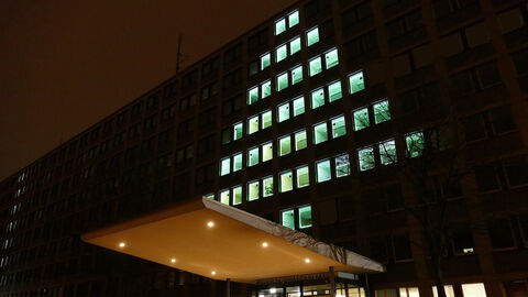 Grün beleuchtete Fenster am RP-Hauptgebäudes in Kassel, die die Form eines Tannenbaumes ergeben.