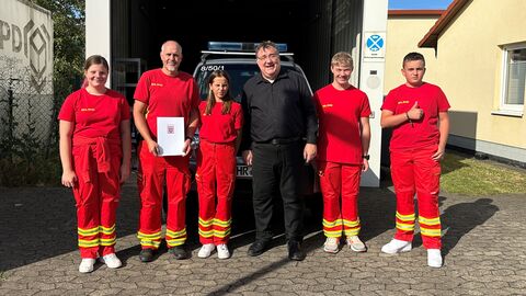 RP Weinmeister übergibt den Förderbescheid an Mitglieder des DLRG.