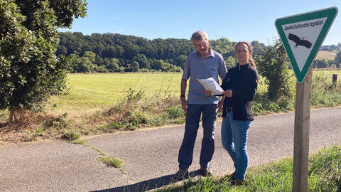 Zwei Personen vor einem Schild mit der Aufschrift "Landschaftsschutzgebiet"