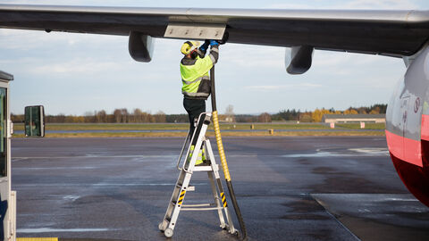 Mann steht auf einer Leiter und arbeitet an einem Flugzeug