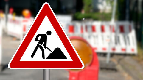 Baustellenschild mit Absperrung im Hintergrund