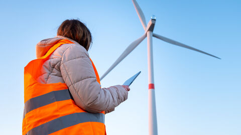Windkraftanlage Mitarbeitende mit Tablet im Vordergrund
