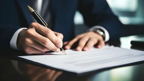 Mann im Anzug unterzeichnet ein Dokument