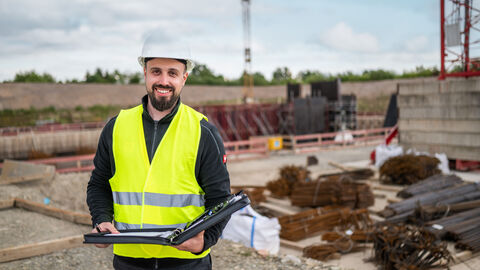Person mit Warnweste auf einer Baustelle. 