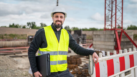 Person mit Warnweste auf einer Baustelle.